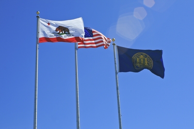 Flags for the State of California, the United States and the University of California fly in the wind at UC Merced.