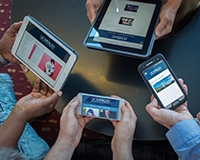 Several sets of hands holding smartphones and tablets.