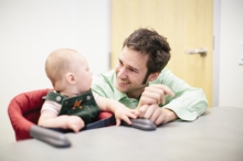 UC Merced Professor Eric Walle smiles at an infant.