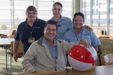 Four staff members from facilities pose with a beach ball.