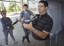 Staff members watch as a man holds and discusses a drone.