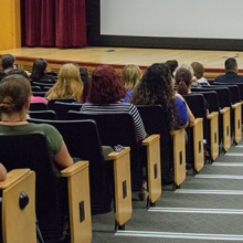 Employees sit in an auditorium waiting for a program to start.