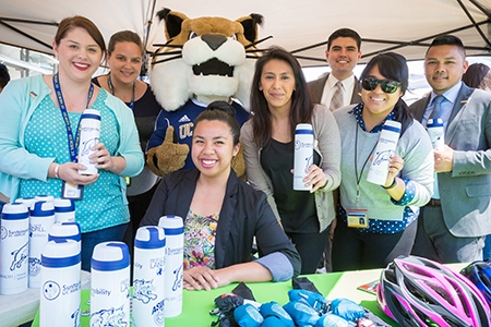 Staff members pose with campus mascot Rufus Bobcat and sustainable water bottles.