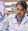 Professor Fabian V. Filipp wears a white lab coat while conducting research in a lab. 