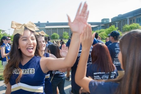 Students high-five each other as they participate in the Scholar's Lane Bridge crossing event at UC Merced.