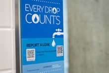 Signage shows restroom visitors how they can report water leaks using their smartphones.