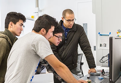 Derek Brigham, Jonny Nguyen and Marek Abarca work in Professor Abel Chuang’s engineering lab.