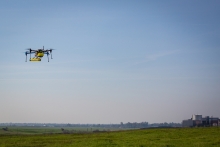 Image of a hovering drone with the UC Merced campus in the background.
