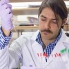 Professor Fabian V. Filipp wears a white lab coat while conducting research in a lab. 